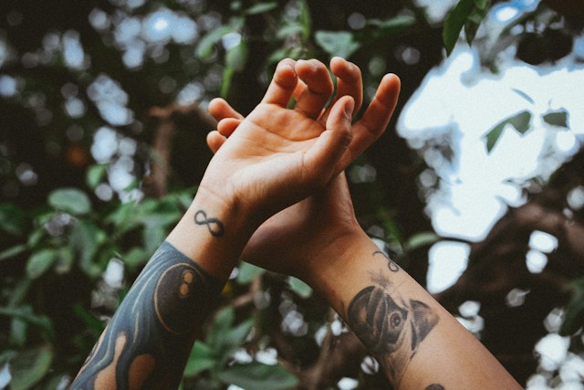 zwei Hände und Unterarme mit Tattoos